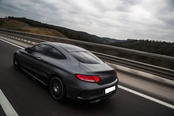 Gümüş krom spor sedan yolda gidiyor. kırmızı ksenon ışıkları