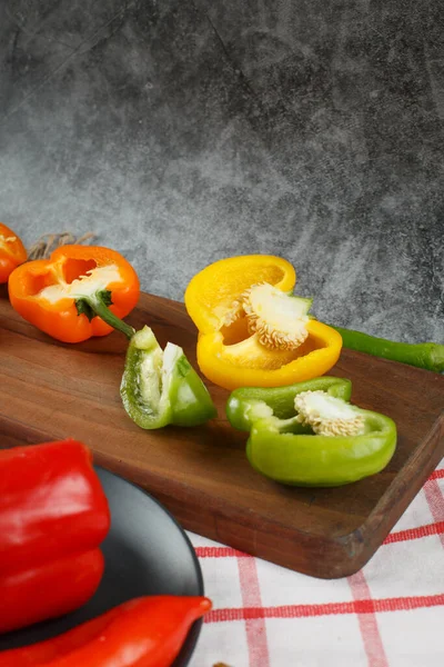 Färgglada chilipeppar skärs på en träskiva. — Stockfoto