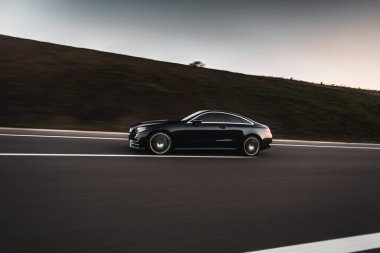 Tepelerden geçen siyah birinci sınıf bir sedan.