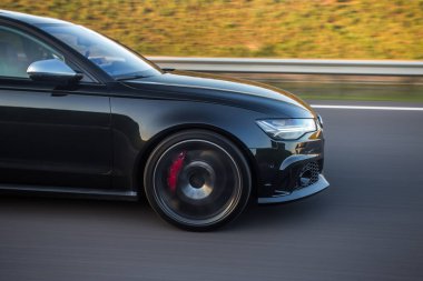 Siyah hatchback tepeleri aşıyor. Ön tampon ve ışıklar.