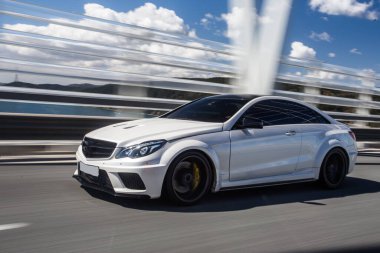 Köprüdeki test sürüşünde beyaz spor sedan.