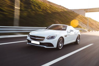 Beyaz spor sedan araba yolda, köprünün altından yeni geçti.