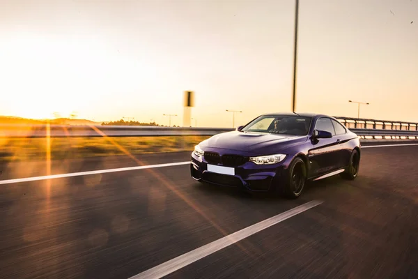 Blue high class sedan on the road in the sunset — Stock Photo, Image