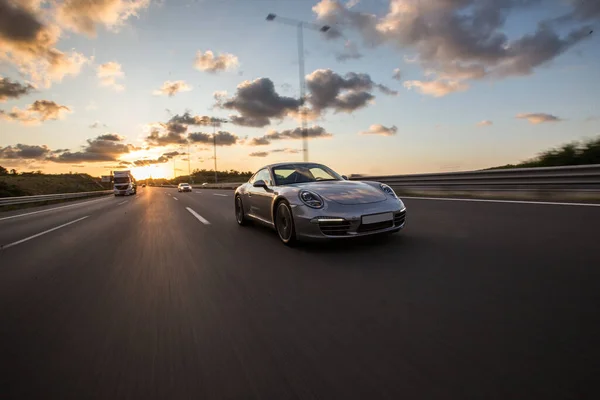 Carro esporte de prata na estrada da montanha ao pôr do sol — Fotografia de Stock