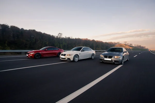 Carros sedan esporte vermelho, branco e prata na estrada — Fotografia de Stock