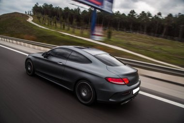 Gümüş krom spor sedan yolda gidiyor. Kırmızı ksenon ışıkları. arka plan