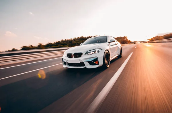 Beyaz sedan güneş ışınları altında otoyolda ilerliyor. ön görünüm