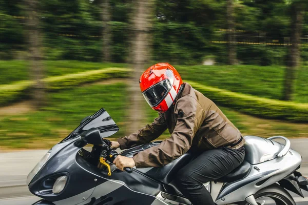 Vélo à grande vitesse sur la route à travers la forêt. chauffeur avec un casque rouge — Photo