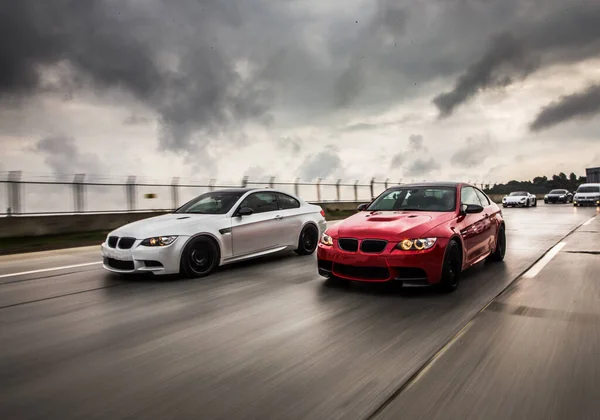 Красные и белые спортивные автомобили, гоняющиеся в тёмную погоду — стоковое фото