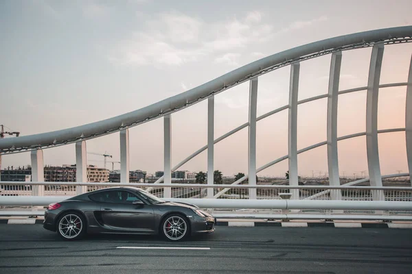 Ένα μαύρο σπορ αυτοκίνητο στη σύγχρονη γέφυρα στο ηλιοβασίλεμα — Φωτογραφία Αρχείου