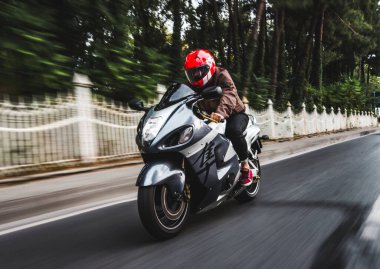 Motosikletli kırmızı kasklı bir motorcu. ön görünüm