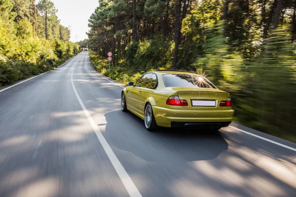 Amarillo viejo modelo sedán conducir en la carretera forestal — Foto de Stock