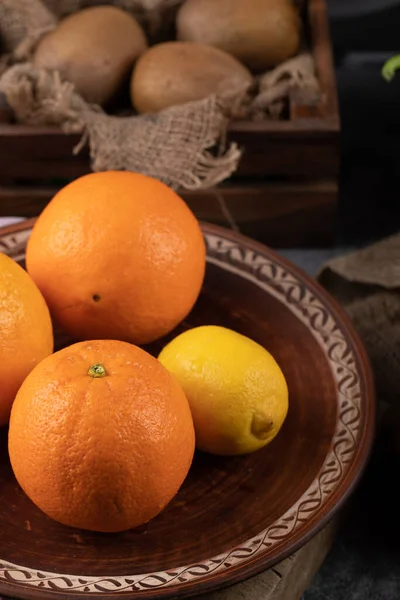 Lemon and oranges in a brown platter. — Stock Photo, Image