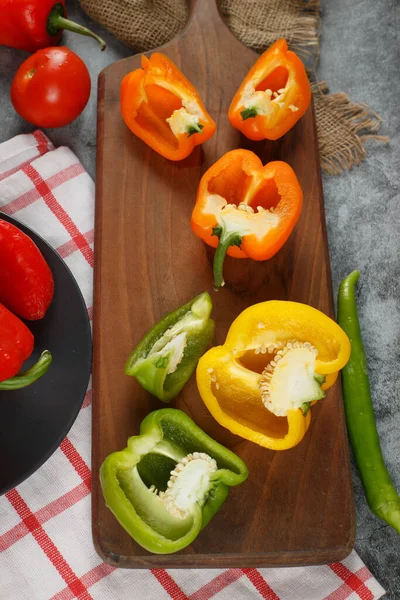 Červená, žlutá a zelená paprika na dřevěné desce. Horní pohled. — Stock fotografie