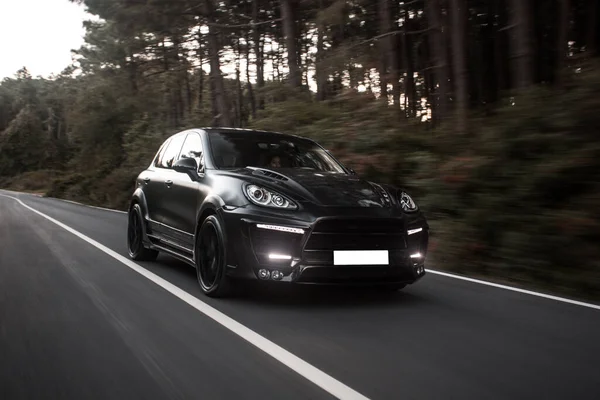 Classe de negócio preto hatchback dirigindo através da floresta — Fotografia de Stock