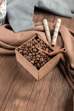 Kahve çekirdekleri ve tarçınlar tahta masada bir kutuda.