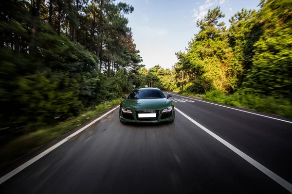 Πράσινο σπορ αυτοκίνητο υψηλής ταχύτητας οδήγηση στο δάσος, μπροστινή άποψη — Φωτογραφία Αρχείου
