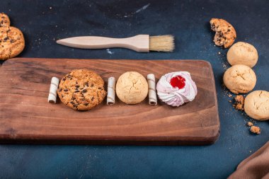Vanilyalı pasta, üzerinde kurabiyeler mavi bir masanın üstünde kesim tahtası.