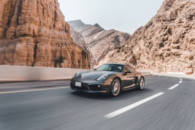 Dağlarda gri renkli bir spor araba sürüyorum.