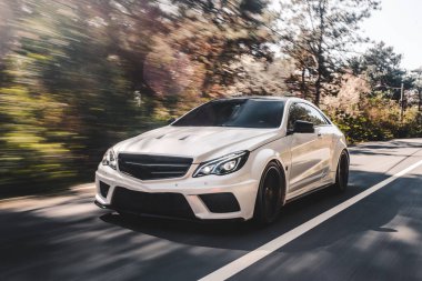 Orman yolunda beyaz spor sedan.