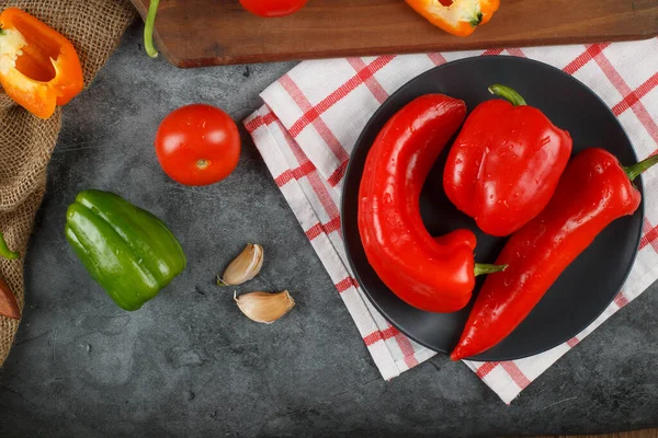 Röda chilipeppar i en svart tallrik på en handduk. Ovanifrån. — Stockfoto