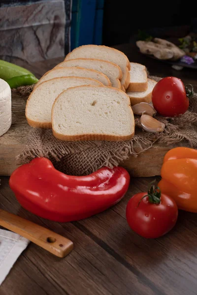 Červené papričky a chléb na dřevěném stole — Stock fotografie