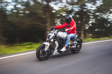 Kırmızı kıyafetli bisikletçi ormanda motosiklet sürüyor.