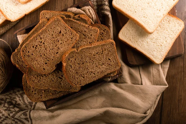 Slices of brown bread in box and white bread on kitchen board