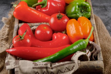 Kırmızı biber, domates ve biber dolu ahşap bir tepsi..