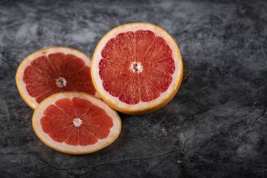 Yarım ve dilimlenmiş greyfurt mermer üzerinde daireler çiziyor.