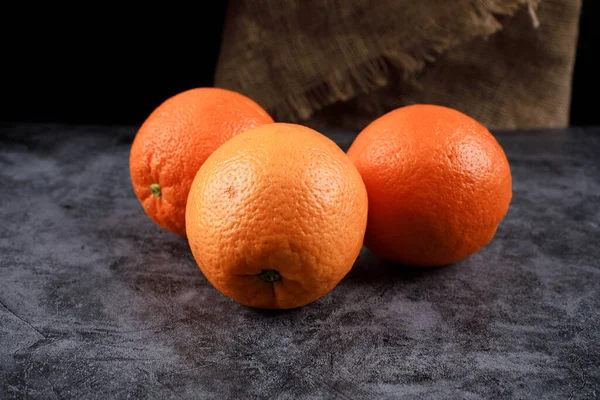 Triángulo enmarcado tres naranjas sobre una mesa azul . — Foto de Stock