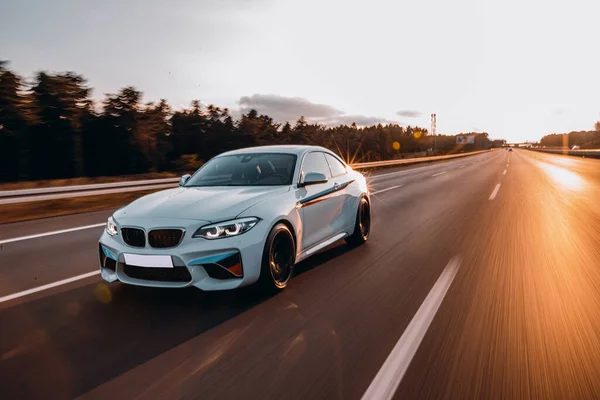 Beyaz birinci sınıf sedan güneş ışığı altında otoyolda gidiyor.