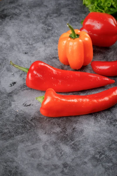 Červené papriky a papriky na kamenném stole. — Stock fotografie