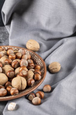 Maviye izole edilmiş dekoratif bir çömlek tabağında karışık fındık.