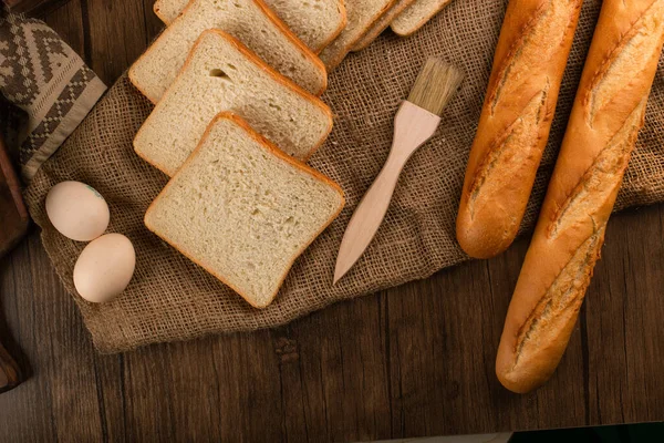 Baguete com fatias de pão branco na toalha de mesa — Fotografia de Stock