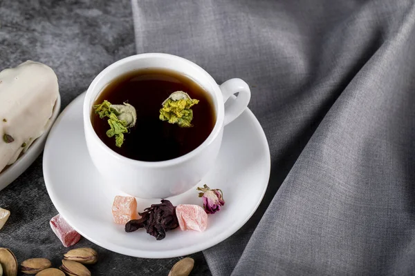 Чашка чая с орехами, турецкий локум и цветы — стоковое фото