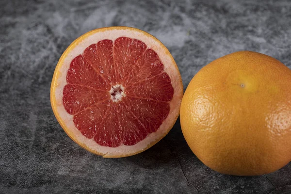 Напіврізаний і цільний грейпфрут на чорному тлі — стокове фото