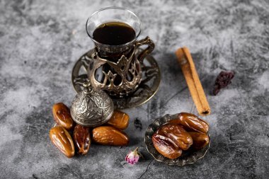 Bir bardak çay ve tarçın çubuklarıyla etnik tarzda bir çay tabağı içinde oryantal tarihler. en üstteki görünüm