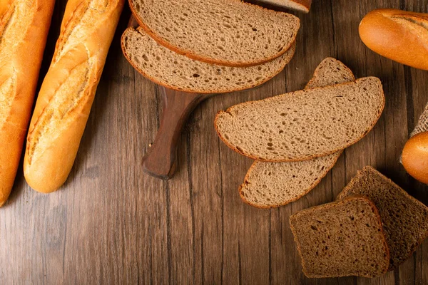 Fatias de pão marrom e branco na placa de cozinha com baguete — Fotografia de Stock