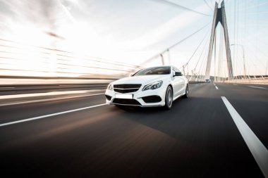 Gündüz vakti köprüden geçen beyaz birinci sınıf bir sedan araba.