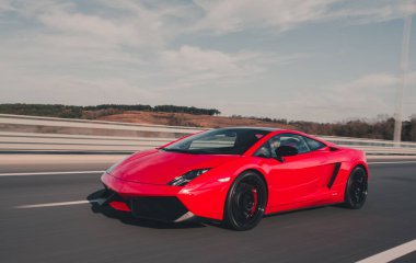 Kırmızı Cabriolet bulutlu gökyüzünün altında sürüyor