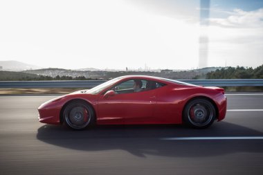 Kırmızı lüks model spor araba otoyolda görünüyor.