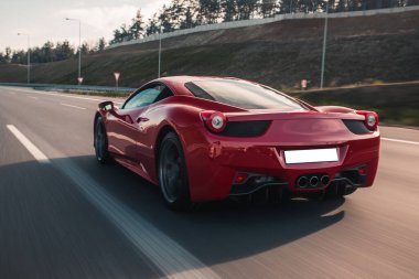 Kırmızı lüks model spor araba arkadan görünüyor.