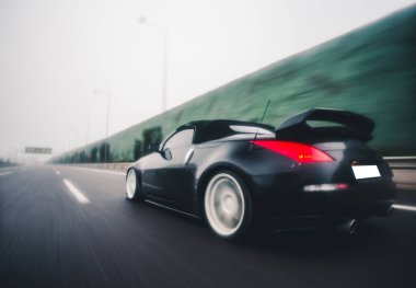 Siyah spor araba. Otobanda yüksek hız. Arka manzara.