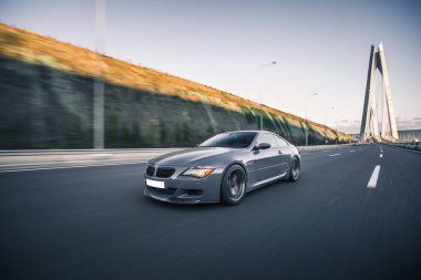 Mavi süper model Cabriolet araba köprünün üstündeki dağlık arazide yol alıyor.