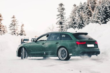 Yeşil off-road aracı karda ormana park ediyor.