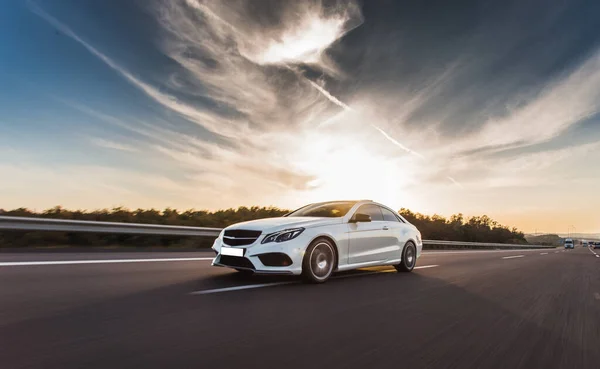 Bianco auto berlina di lusso guida sulla strada sotto le nuvole di sole — Foto Stock