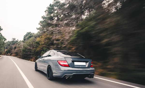 Cabriolet blu con luci rosse allo xeno sulla strada forestale a sinistra — Foto Stock