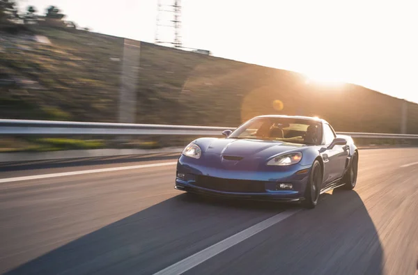 Coche modelo deportivo de marca azul, conducción de prueba de alta velocidad en el tiempo de puesta del sol — Foto de Stock