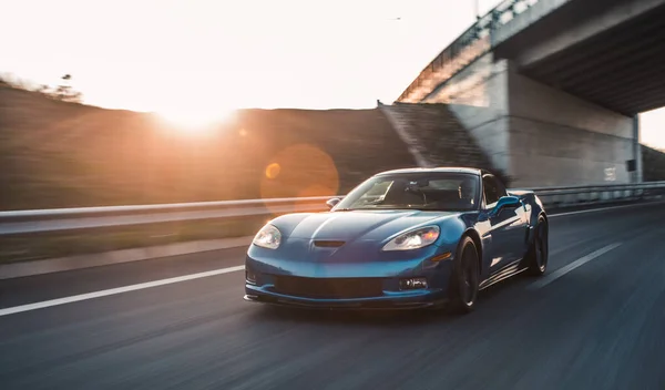 Carro modelo do esporte da marca azul, movimentação de teste de alta velocidade sob a ponte no tempo do por do sol — Fotografia de Stock